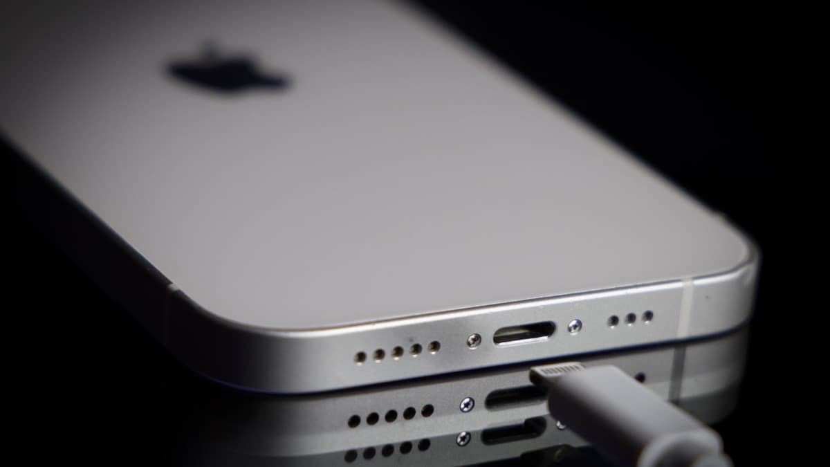 An iPhone lying beside a USB-C charging cable