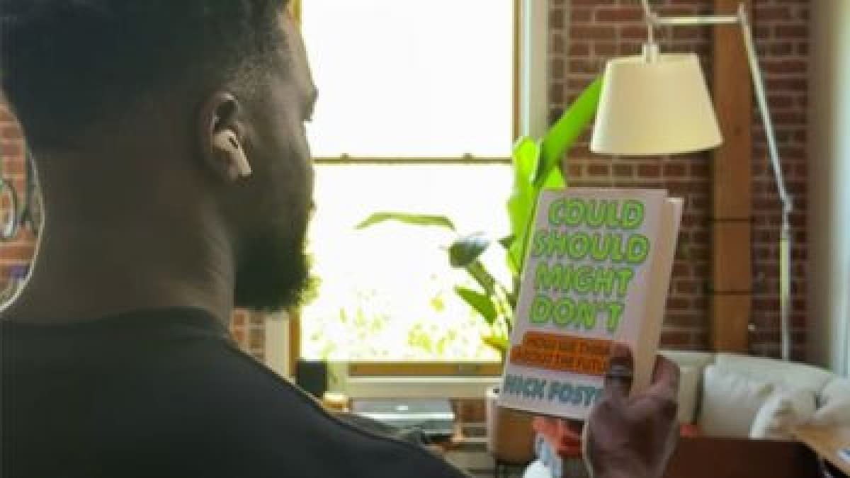 Man wearing AirPods holds up a book in Apple's Visual Intelligence demo video